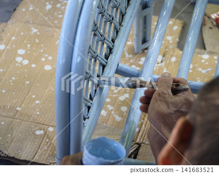 Blue paint brush furniture wicker hand blue paint brush wicker furniture during repair Blue paint brush furniture wicker hand blue paint brush wicker furniture during repair 141683521