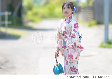 A woman in a yukata looks back, a summer scene on a country road. A woman in a yukata looks back, a summer scene on a country road. 141683636