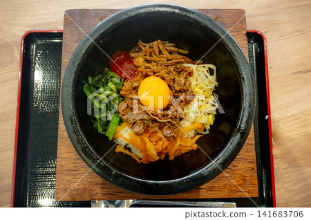 Stone pot bibimbap, a Korean dish with egg yolk and colorful vegetables. Stone pot bibimbap, a Korean dish with egg yolk and colorful vegetables. 141683706