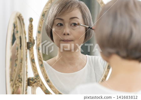 一位老年婦女在鏡子前化妝。 141683812