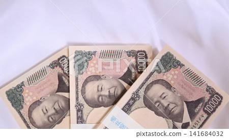 A stack of 10,000 yen bills placed on a cloth. 141684032