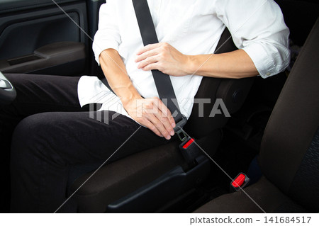 Hands of a person wearing a car seatbelt Hands of a person wearing a car seatbelt 141684517
