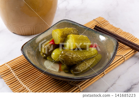 bowl of crunchy Russian pickled cucumbers gherkins with brine and chopsticks, traditional appetizer bowl of crunchy Russian pickled cucumbers gherkins with brine and chopsticks, traditional appetizer 141685223