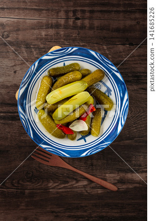 bowl of crunchy Russian pickled cucumbers gherkins with brine and chopsticks on dark wooden table, traditional appetizer bowl of crunchy Russian pickled cucumbers gherkins with brine and chopsticks on dark wooden table, traditional appetizer 141685226