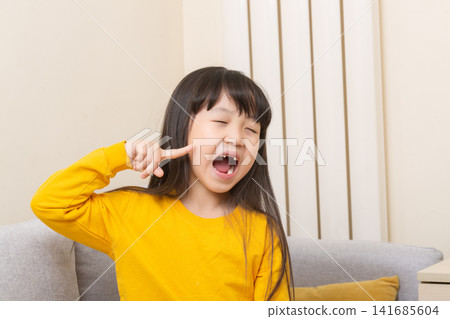Asian girl pointing to open mouth with tooth pain, child showing dental problem at home, healthcare concept Asian girl pointing to open mouth with tooth pain, child showing dental problem at home, healthcare concept 141685604