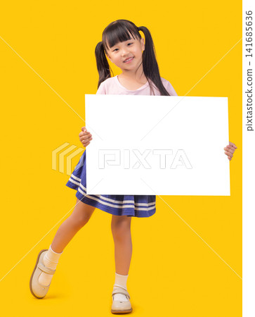 Smiling elementary age girl holding a large blank white presentation board horizontally with both hands in front of a yellow studio backdrop. Smiling elementary age girl holding a large blank white presentation board horizontally with both hands in front of a yellow studio backdrop. 141685636