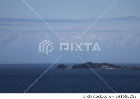 A landscape of clouds, blue sky, the horizon, the blue sea, and an island with buildings. A landscape of clouds, blue sky, the horizon, the blue sea, and an island with buildings. 141686282