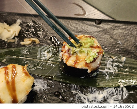 Tempura sushi rolls with creamy cheese topping served with wasabi pickled ginger and unagi sauce on black plate 141686508