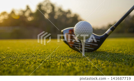 Golf clubs and balls on a green lawn in a beautiful golf course with morning sunshine. Golf clubs and balls on a green lawn in a beautiful golf course with morning sunshine. 141687719