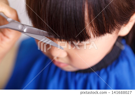 Cute Asian Little Girl Getting Haircut at Home With Different Emotions Cute Asian Little Girl Getting Haircut at Home With Different Emotions 141688027