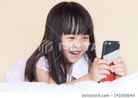 Asian Little Girl Using Smartphone on Bed Showing Different Emotions Asian Little Girl Using Smartphone on Bed Showing Different Emotions 141688049