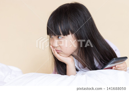 Cute Asian Little Girl Feeling Sad and Unhappy on Bed Indoors, Emotional Child Hugging Pillow in Warm Cozy Bedroom Cute Asian Little Girl Feeling Sad and Unhappy on Bed Indoors, Emotional Child Hugging Pillow in Warm Cozy Bedroom 141688050
