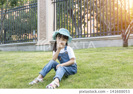 Happy Asian Little Girl Playing on Green Grass in Summer Park Happy Asian Little Girl Playing on Green Grass in Summer Park 141688053