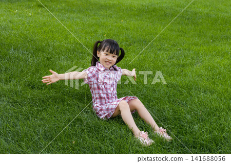 Happy Asian Little Girl Playing on Green Grass in Summer Park Happy Asian Little Girl Playing on Green Grass in Summer Park 141688056