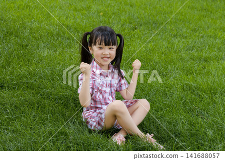 Happy Asian Little Girl Playing on Green Grass in Summer Park Happy Asian Little Girl Playing on Green Grass in Summer Park 141688057