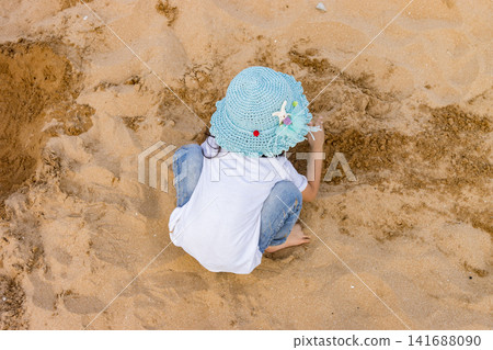 Asian Little Girl Playing With Sand on Beach During Summer Vacation Asian Little Girl Playing With Sand on Beach During Summer Vacation 141688090