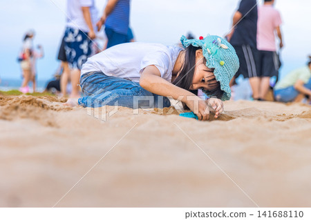 Asian Little Girl Playing With Sand on Beach During Summer Vacation Asian Little Girl Playing With Sand on Beach During Summer Vacation 141688110