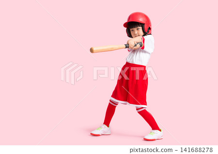Full length shot of a young girl swinging a wooden baseball bat against a solid pink background. Full length shot of a young girl swinging a wooden baseball bat against a solid pink background. 141688278
