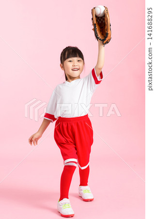 Athletic young girl throwing a baseball while wearing a leather mitt on a pink background. 141688295