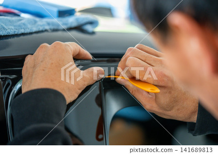 A car wrapping specialist applies a polyurethane film to the car. Detailer PPF A car wrapping specialist applies a polyurethane film to the car. Detailer PPF 141689813