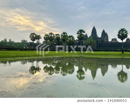 An Instagram-worthy photo of Angkor Wat reflected on the water's surface, illuminated by the rising sun (an inverted Angkor Wat). An Instagram-worthy photo of Angkor Wat reflected on the water's surface, illuminated by the rising sun (an inverted Angkor Wat). 141690031