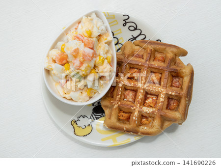 Golden-brown savory waffle topped with sesame seeds and chicken floss, complemented by a smooth egg, chicken breast, corn, green peas and carrot salad. Golden-brown savory waffle topped with sesame seeds and chicken floss, complemented by a smooth egg, chicken breast, corn, green peas and carrot salad. 141690226