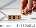 Hand Holding Wooden Number Block to Change 2026 into 2027 New Year Concept 141690618