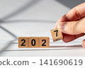 Hand Holding Wooden Number Block to Change 2026 into 2027 New Year Concept 141690619