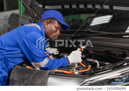 Professional EV Car Service, Male worker Electricity Vehicle Fix Maintenance in EV Garage workshop. Professional EV Car Service, Male worker Electricity Vehicle Fix Maintenance in EV Garage workshop. 141690690