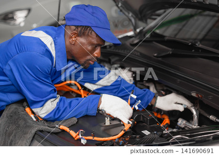 Professional EV Car Service, Male worker Electricity Vehicle Fix Maintenance in EV Garage workshop. Professional EV Car Service, Male worker Electricity Vehicle Fix Maintenance in EV Garage workshop. 141690691