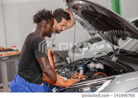 Professional EV Car Service, Male workers Electricity Vehicle Fix Maintenance in EV Garage workshop. Professional EV Car Service, Male workers Electricity Vehicle Fix Maintenance in EV Garage workshop. 141690768
