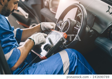 Professional mechanic using OBD2 scanner to inspect vehicle. Car diagnostic and maintenance service. Professional mechanic using OBD2 scanner to inspect vehicle. Car diagnostic and maintenance service. 141690789