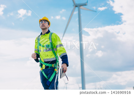 Professional engineer male working outdoors with safety. Wind turbines clean energy power station. Professional engineer male working outdoors with safety. Wind turbines clean energy power station. 141690916