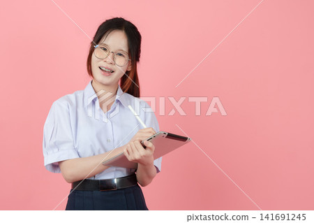 Young Student eyeglasses uniform with tablet, Asian teen girl cute pretty happy smiling learning. Young Student eyeglasses uniform with tablet, Asian teen girl cute pretty happy smiling learning. 141691245