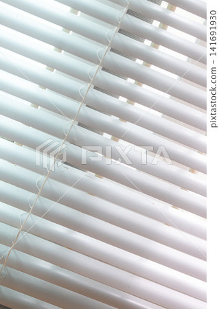 Close-up of sunlight passing through window blinds, creating abstract geometric lines and soft shadows Close-up of sunlight passing through window blinds, creating abstract geometric lines and soft shadows 141691930