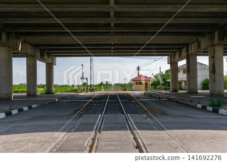 Railway crossing beneath concrete highway bridge tracks leading to horizon rural transport infrastructure engineering perspective under daylight open landscape Railway crossing beneath concrete highway bridge tracks leading to horizon rural transport infrastructure engineering perspective under daylight open landscape 141692276