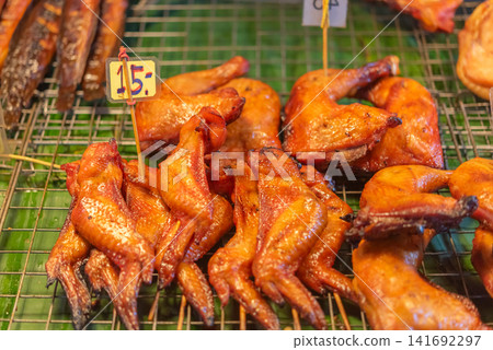 Golden roasted chicken displayed at street food market crispy skin rich flavor ready for takeaway local cuisine barbecue meals fresh serving Golden roasted chicken displayed at street food market crispy skin rich flavor ready for takeaway local cuisine barbecue meals fresh serving 141692297