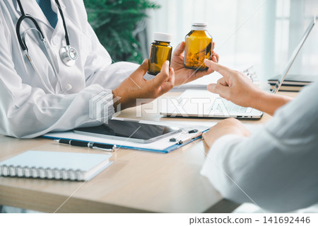 Doctor holding prescription medicine bottles and explaining medication to patient during clinic visit, pharmacy, dosage advice, treatment plan, and healthcare concept. Doctor holding prescription medicine bottles and explaining medication to patient during clinic visit, pharmacy, dosage advice, treatment plan, and healthcare concept. 141692446