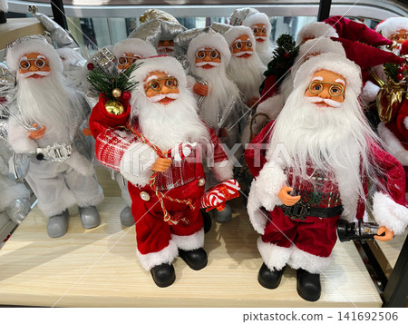 Santa figures holding small festive props and decorated in holiday outfits. The scene expresses the concept of cheerful winter celebration Santa figures holding small festive props and decorated in holiday outfits. The scene expresses the concept of cheerful winter celebration 141692506
