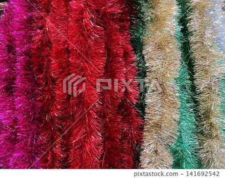 Rows of tinsel in red, pink, gold and green displayed together. A concept of festive color selection and holiday decoration variety Rows of tinsel in red, pink, gold and green displayed together. A concept of festive color selection and holiday decoration variety 141692542