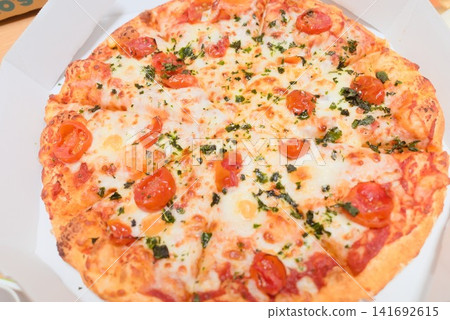Freshly baked whole pizza topped with cherry tomatoes and cheese. Freshly baked whole pizza topped with cherry tomatoes and cheese. 141692615