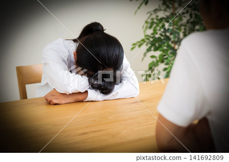 一名穿著校服的中學生在客廳的桌子上崩潰大哭。 一名穿著校服的中學生在客廳的桌子上崩潰大哭。 141692809