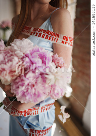 Woman with pink peonies wrapped in 'fragile' Russian tape Woman with pink peonies wrapped in 'fragile' Russian tape 141693119