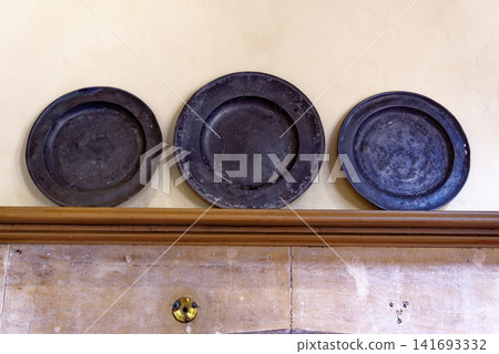 Antique pewter plates and ceramic earthenware jars on wooden dresser shelves at Dyrham Park Antique pewter plates and ceramic earthenware jars on wooden dresser shelves at Dyrham Park 141693332