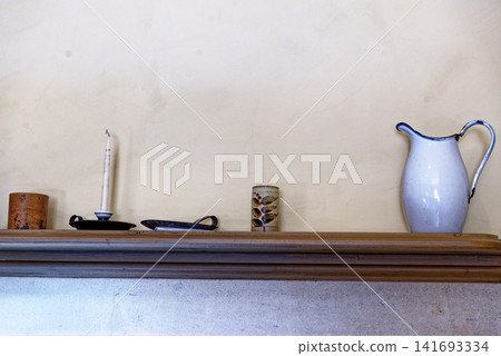Antique white enamel pitcher and vintage chamberstick candle holder on a kitchen mantelpiece at Dyrham Park Antique white enamel pitcher and vintage chamberstick candle holder on a kitchen mantelpiece at Dyrham Park 141693334