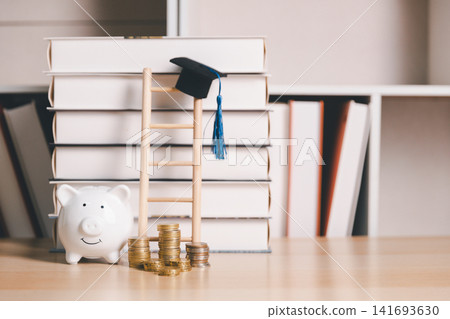 Piggy bank, coin stacks, wooden ladder, books, and graduation cap symbolize step-by-step education savings, academic achievement, career growth, and financial planning for university. Piggy bank, coin stacks, wooden ladder, books, and graduation cap symbolize step-by-step education savings, academic achievement, career growth, and financial planning for university. 141693630