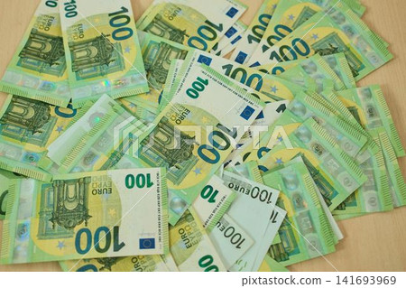 One hundred euro banknotes are scattered across the surface in a layered cash arrangement. High value currency concept for savings, payment, banking and financial planning One hundred euro banknotes are scattered across the surface in a layered cash arrangement. High value currency concept for savings, payment, banking and financial planning 141693969