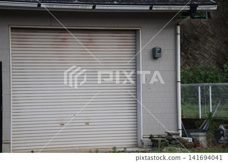 A view of a closed-shutter warehouse with a garden. A view of a closed-shutter warehouse with a garden. 141694041