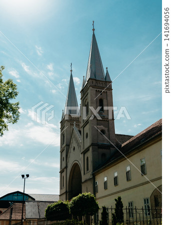 Catholic Church of Saint Francis of Assisi in Subotica, Serbia under bright blue sky. Twin towers and sacred architecture in warm sunlight Catholic Church of Saint Francis of Assisi in Subotica, Serbia under bright blue sky. Twin towers and sacred architecture in warm sunlight 141694056