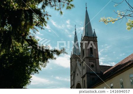 Catholic Church of Saint Francis of Assisi in Subotica, Serbia under bright blue sky. Twin towers and sacred architecture in warm sunlight Catholic Church of Saint Francis of Assisi in Subotica, Serbia under bright blue sky. Twin towers and sacred architecture in warm sunlight 141694057